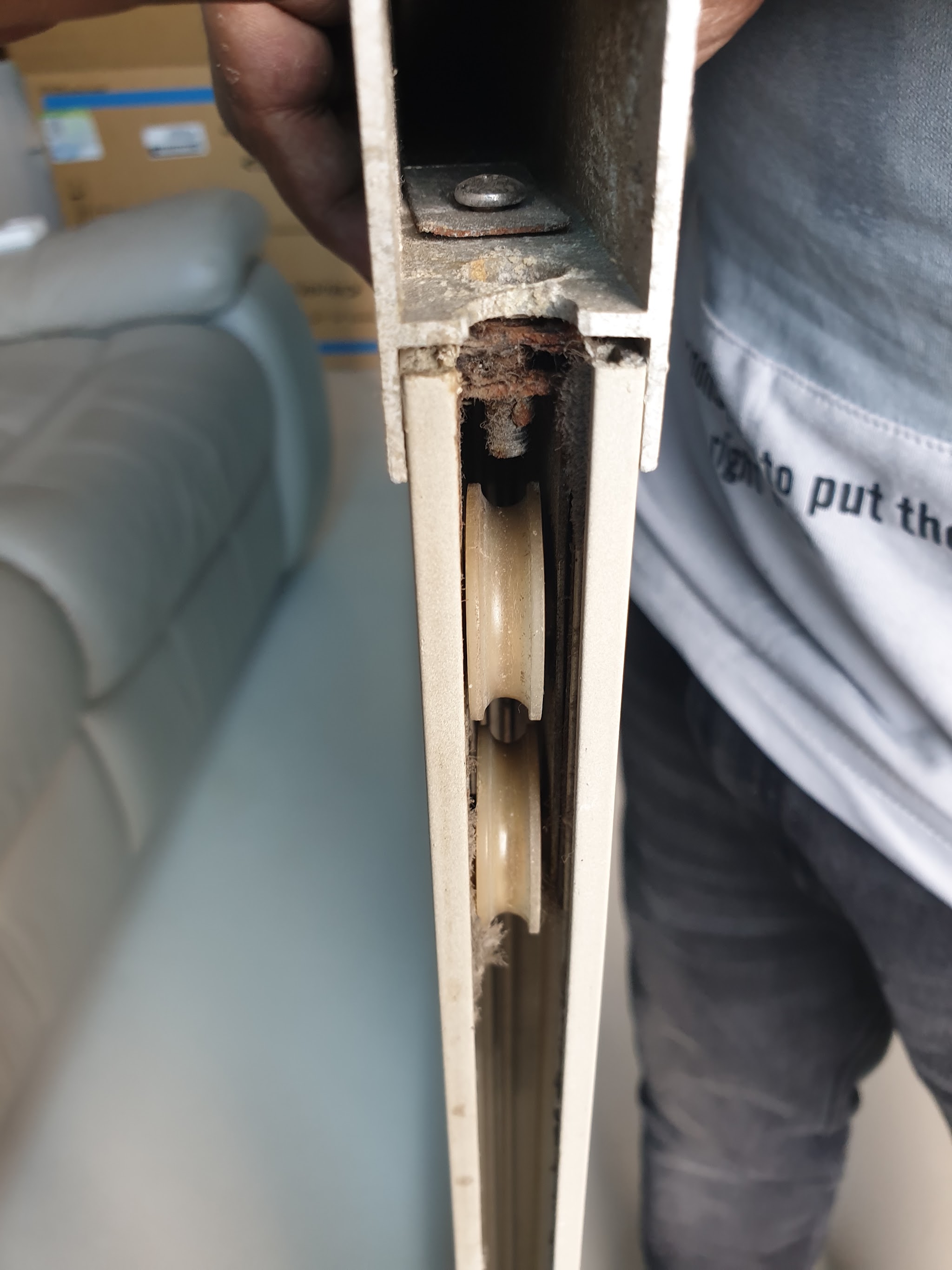 A sliding door stile opened up, showing the roller mechanism and packed grit inside the track